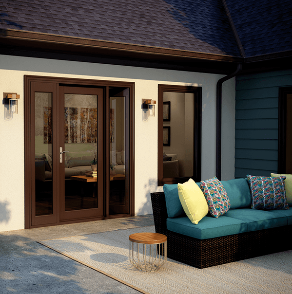 Milgard(swing) A patio with a wicker sofa featuring colorful cushions, a small round table on a light rug, and a modern house with glass doors and windows.